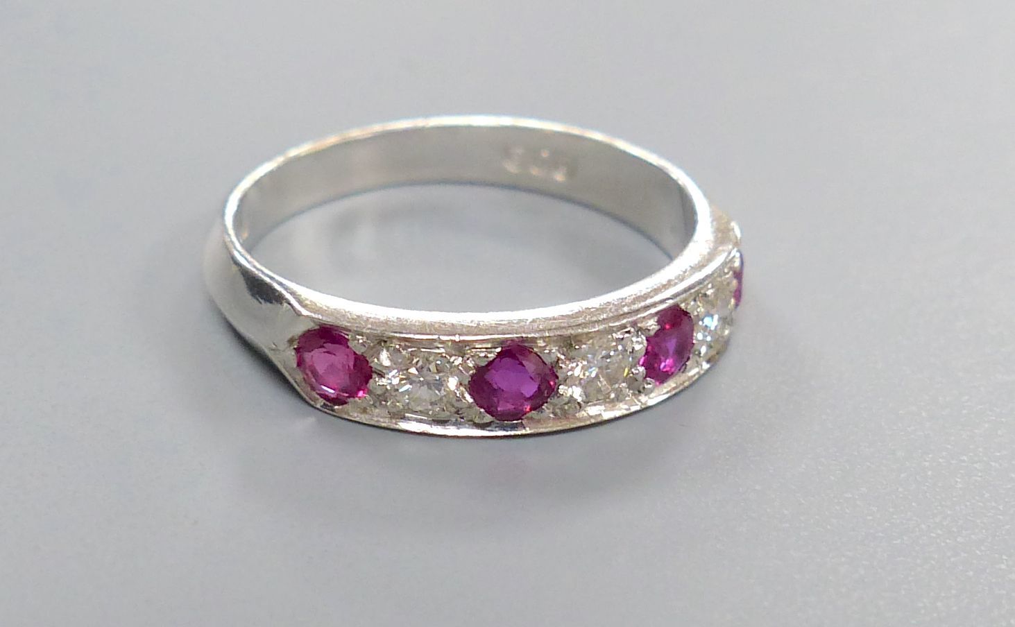 A modern 18ct white gold, four stone ruby and three stone diamond set half hoop ring, size M, gross 3.7 grams.